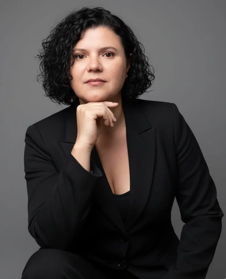 Rosemary Maria do Carmo de blazer preto, com a mão no queixo, em fundo cinza